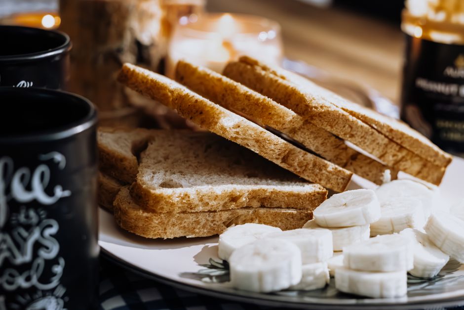 Warm breakfast scene with sliced bread, bananas, and coffee, evoking a cozy morning vibe.