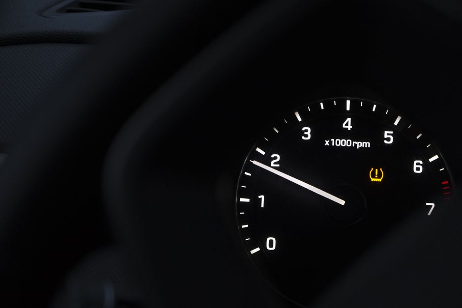 A detailed view of a car tachometer showing RPM with tire pressure warning.